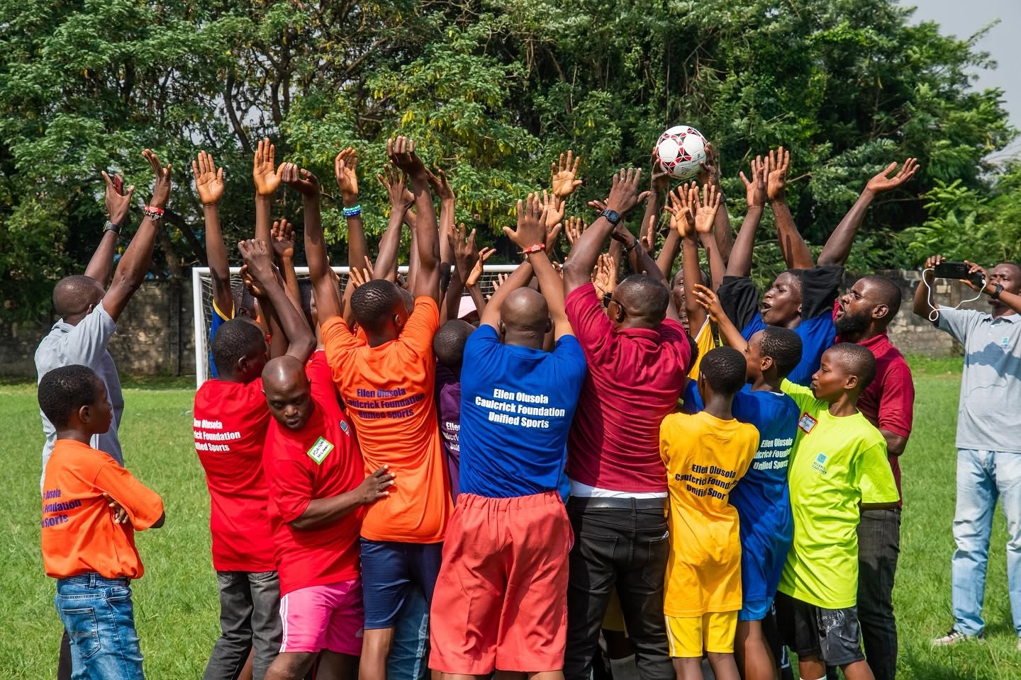 EOCF Unified Sports participants reaching together for a football on a grassy field